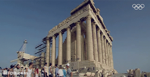 A Group Of People Standing In Front Of A Building With The Olympics Logo In The Background GIF