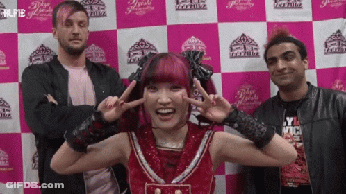 A Group Of People Standing In Front Of A Pink And White Checkered Wall With The Word Tokyo On It GIF