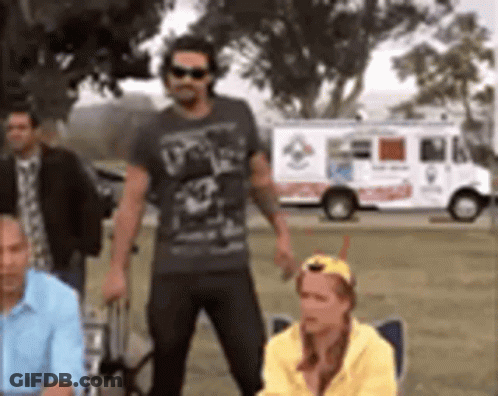A Group Of People Standing In Front Of A Pizza Truck . GIF
