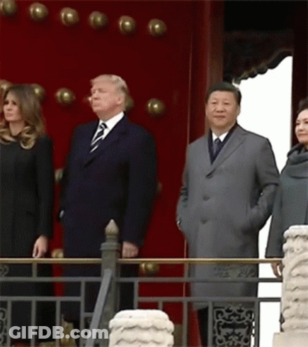 A Group Of People Standing In Front Of A Red Wall GIF