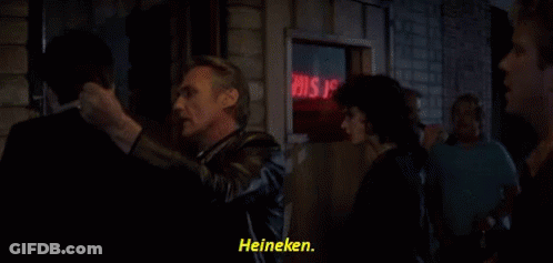 A Group Of People Standing In Front Of A Sign That Says Heineken GIF
