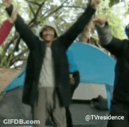 A Group Of People Standing In Front Of A Tent With Their Hands In The Air . GIF