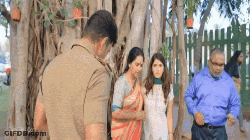 A Group Of People Standing In Front Of A Tree With A Man In A Police Uniform GIF