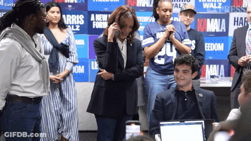A Group Of People Standing In Front Of A Wall That Says Kamala On It GIF