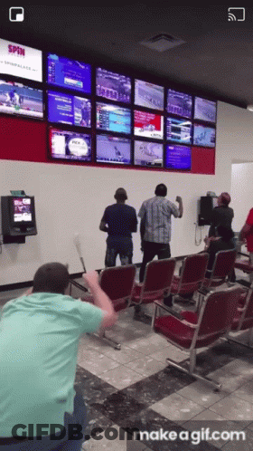 A Group Of People Standing In Front Of A Wall With A Screen That Says Spin GIF