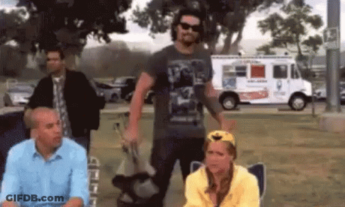 A Group Of People Standing In Front Of An Ice Cream Truck In A Park . GIF
