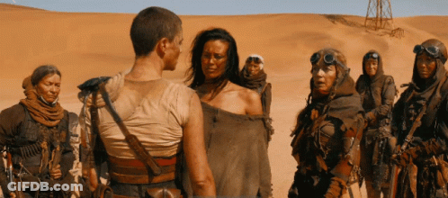 A Group Of People Standing In The Desert With One Wearing A Goggles GIF