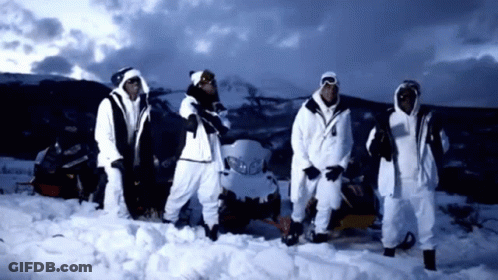 A Group Of People Standing In The Snow In Front Of A Snowmobile GIF