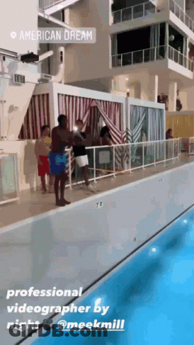 A Group Of People Standing Next To A Swimming Pool With A Sign That Says American Dream On It GIF