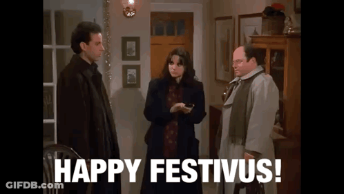 A Group Of People Standing Next To Each Other In A Living Room With The Words `` Happy Festivus '' Written On The Screen GIF