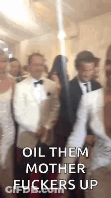 A Group Of People Standing Next To Each Other In A Room With The Words `` Oil Them Mother Fuckers Up '' Written On The S GIF