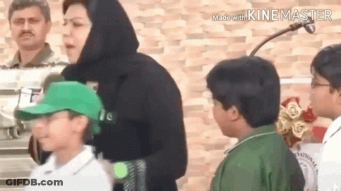 A Group Of People Standing Next To Each Other In Front Of A Brick Wall . GIF
