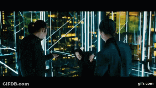 A Group Of People Standing Next To Each Other In Front Of A Building . GIF