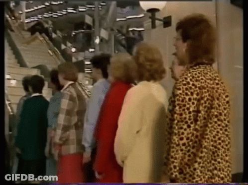 A Group Of People Standing Next To Each Other In Front Of A Staircase GIF