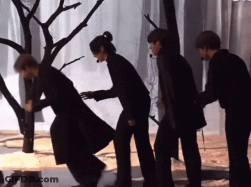 A Group Of People Standing Next To Each Other In Front Of A Tree GIF