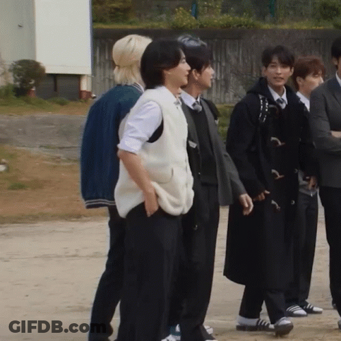 A Group Of People Standing Next To Each Other With One Wearing A Vest GIF