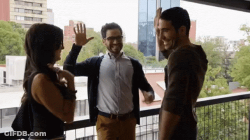 A Group Of People Standing On A Balcony Giving Each Other A High Five GIF