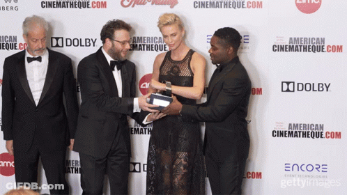 A Group Of People Standing On A Red Carpet With A Sign That Says Dolby GIF