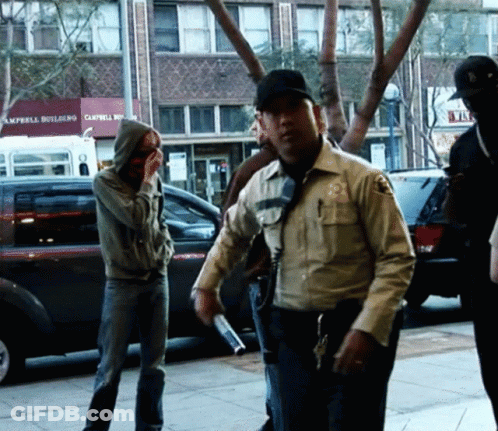A Group Of People Standing On A Sidewalk In Front Of A Building That Says Campbell Building GIF
