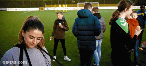A Group Of People Standing On A Soccer Field Eating Hamburgers GIF