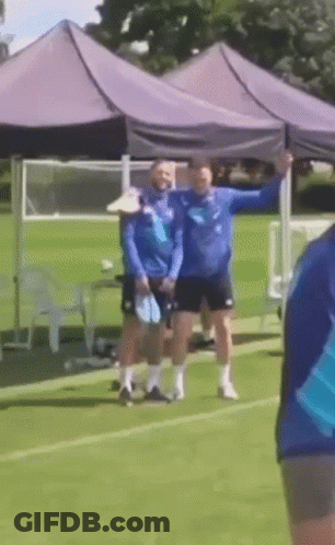 A Group Of People Standing On A Soccer Field Under A Purple Tent GIF
