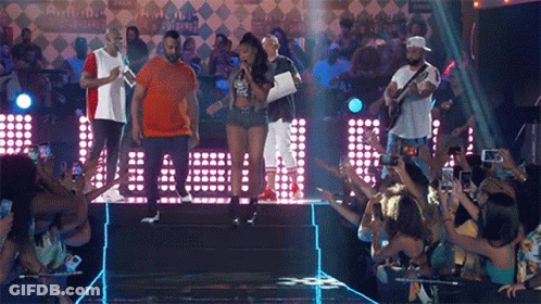 A Group Of People Standing On A Stage In Front Of A Crowd Taking Pictures GIF