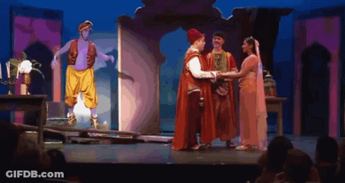 A Group Of People Standing On A Stage With A Man In A Turban Standing Behind Them GIF
