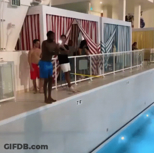 A Group Of People Standing On The Edge Of A Swimming Pool With The Number 70 On The Side GIF