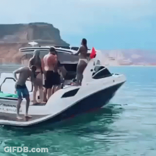 A Group Of People Standing On Top Of A Boat In The Water . GIF