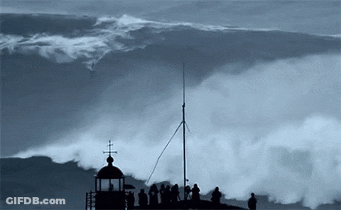 A Group Of People Standing On Top Of A Tower Watching A Large Wave GIF