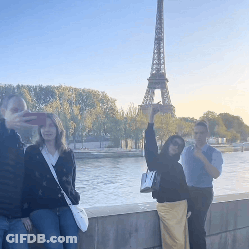 A Group Of People Taking A Picture Of The Eiffel Tower In Paris GIF
