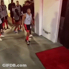 A Group Of People Walking Down A Hallway With A Red Rug GIF