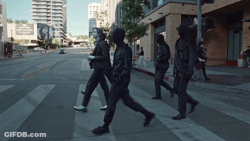 A Group Of People Walking Down A Street In Front Of A Sign That Says ' Now Leasing ' GIF