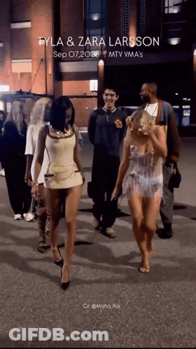 A Group Of People Walking Down A Street With The Words Tyla & Zara Larsson Written On The Bottom GIF