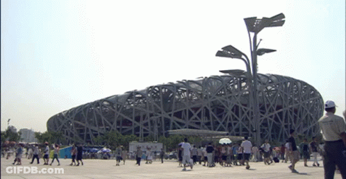 A Group Of People Walking In Front Of A Large Building GIF