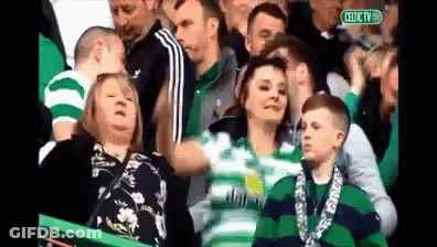 A Group Of People Watching A Soccer Game With A Sign That Says Celtic Tv GIF