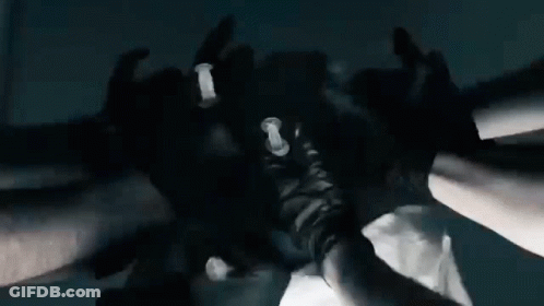A Group Of People Wearing Black Gloves Are Putting Their Hands Together In A Huddle . GIF