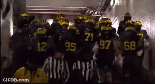 A Group Of People Wearing Black Uniforms With Yellow Numbers On Them GIF