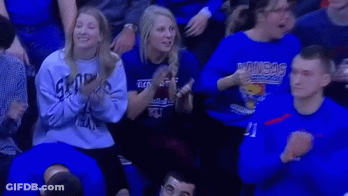 A Group Of People Wearing Blue Shirts Are Sitting In A Stadium Watching A Game . GIF