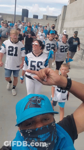 A Group Of People Wearing Carolina Panthers Jerseys Are Walking GIF