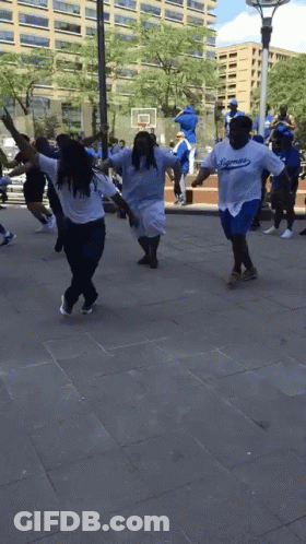 A Group Of People Wearing Dodgers Shirts Are Dancing On The Sidewalk GIF