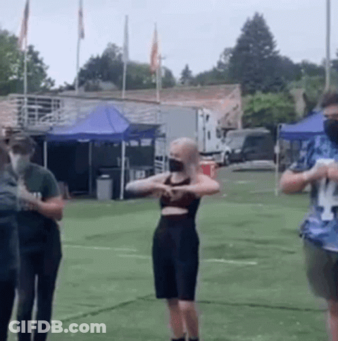 A Group Of People Wearing Face Masks Are Standing On Top Of A Field . GIF