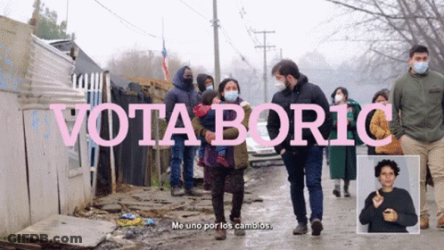 A Group Of People Wearing Face Masks Are Walking Down A Street With The Words Vota Boric In Pink GIF