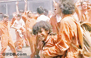 A Group Of People Wearing Orange Jumpsuits Are Standing In A Crowd . GIF