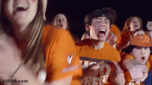 A Group Of People Wearing Orange Shirts And Hats Are Standing In A Crowd . GIF