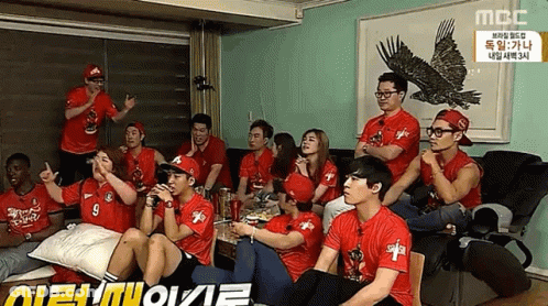 A Group Of People Wearing Red Shirts With The Number 9 On Them Are Sitting Around A Table GIF