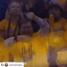 A Group Of People Wearing Yellow Shirts Are Watching A Game . GIF
