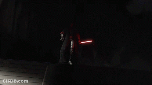 A Group Of People With Red Lightsabers In The Dark GIF