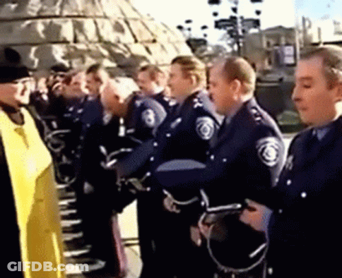 A Group Of Police Officers Are Standing In A Line Talking To Each Other . GIF