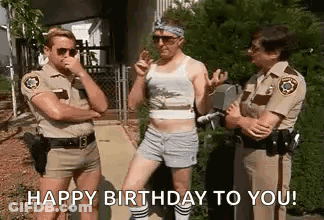 A Group Of Police Officers Are Standing Next To Each Other On A Sidewalk And One Of Them Is Wearing Shorts . GIF